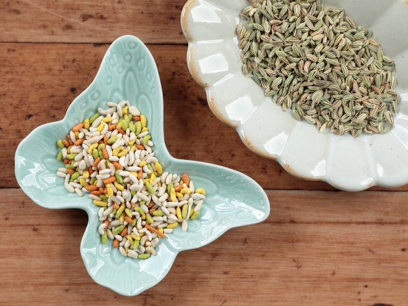 蝶の形の小皿にシュガーコーティングされたカラフルなソーンフが入っており、右手に写る楕円小皿に入っているフェンネルのタネと比較できる写真